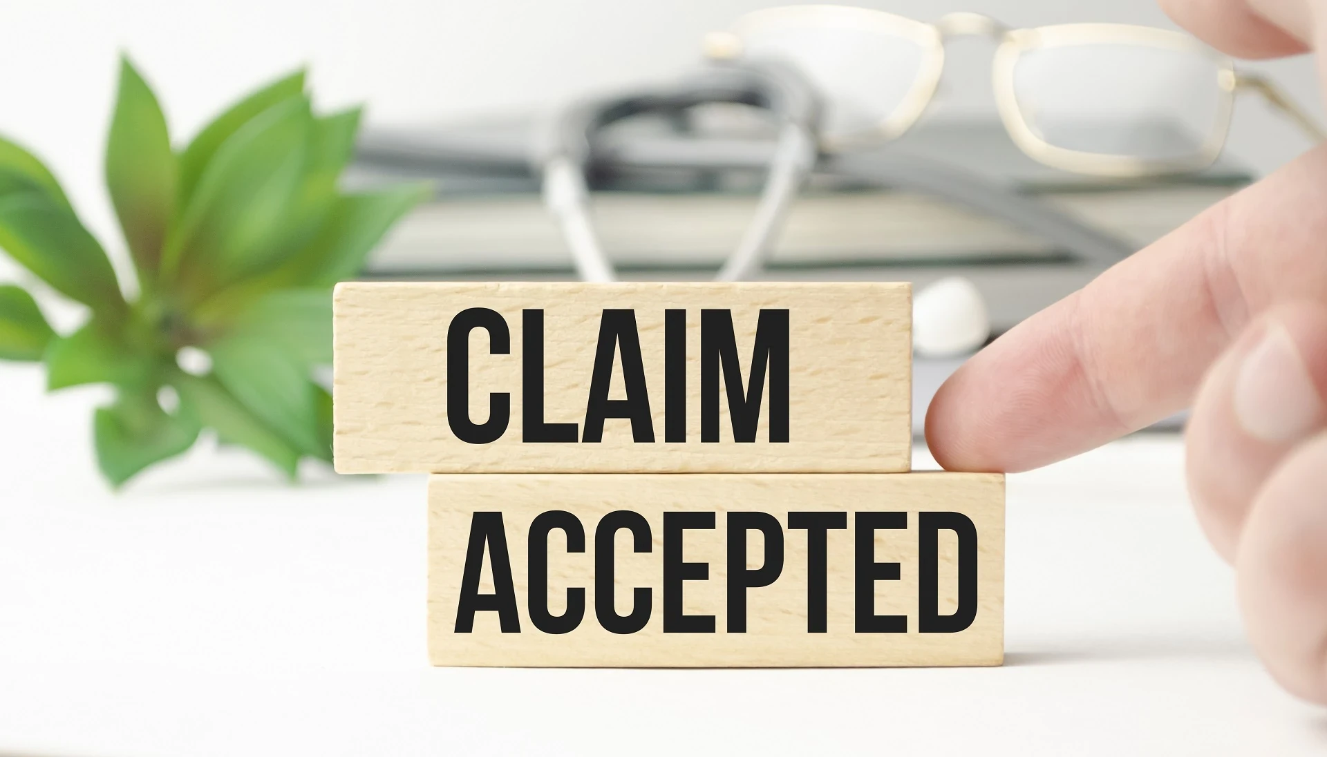 User pointing to wooden blocks that read Claim Accepted.