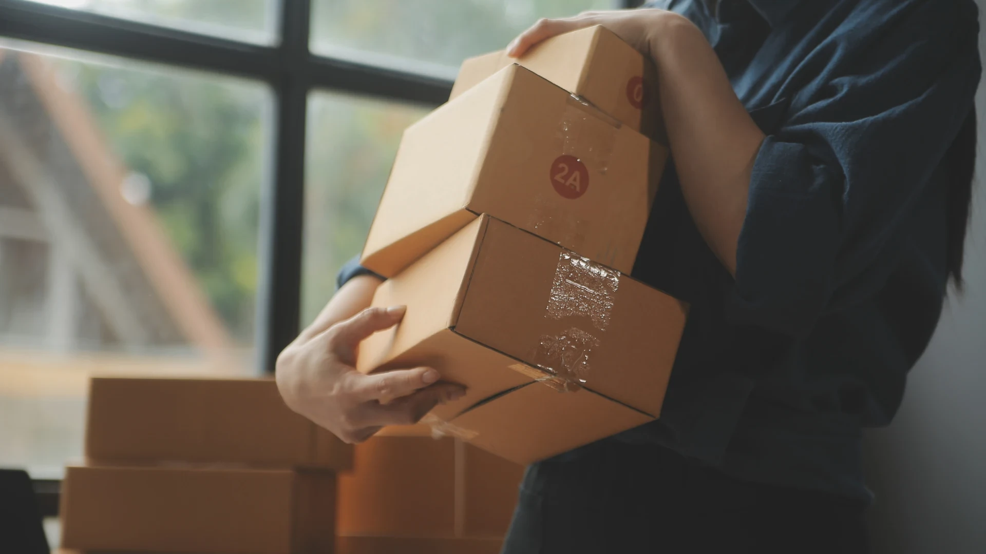 A member of staff at their workplace is trying to carry several large parcels for internal delivery.