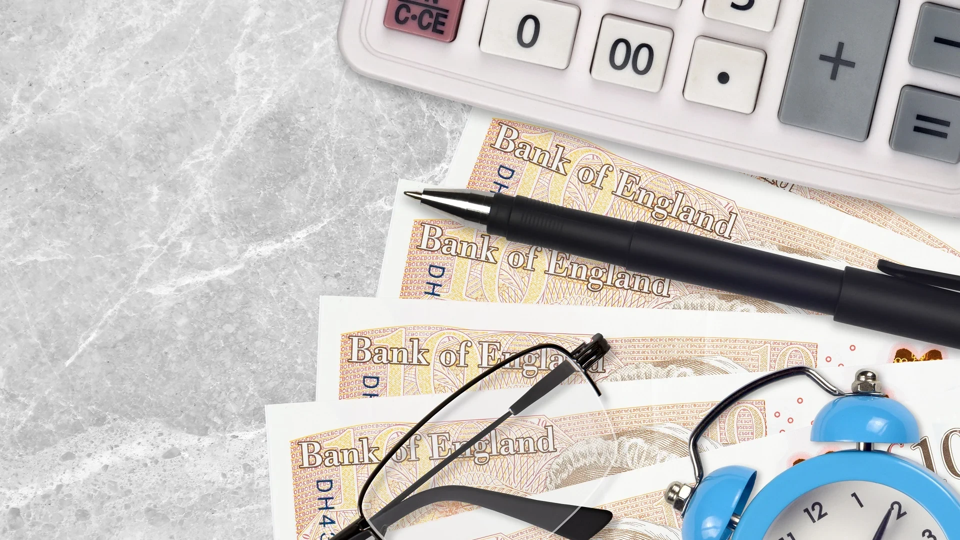 Underneath a calculator, pen, glasses are a series of £10 bank notes, highlighting a cut wages through a workplace accident.
